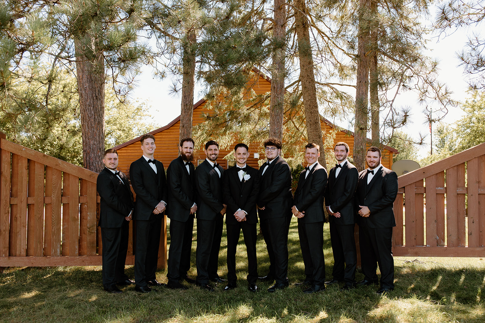 Groomsmen smile in a line in front of the camera