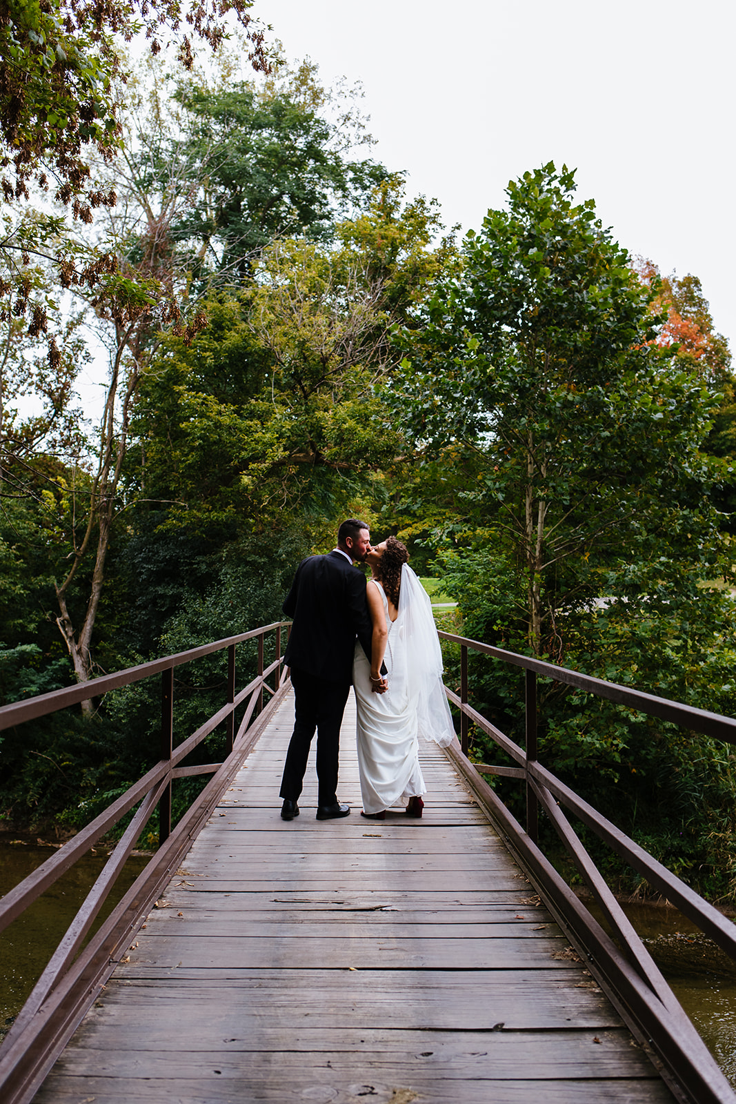 Bride and groom kiss on a bridge in Syracuse, NY.