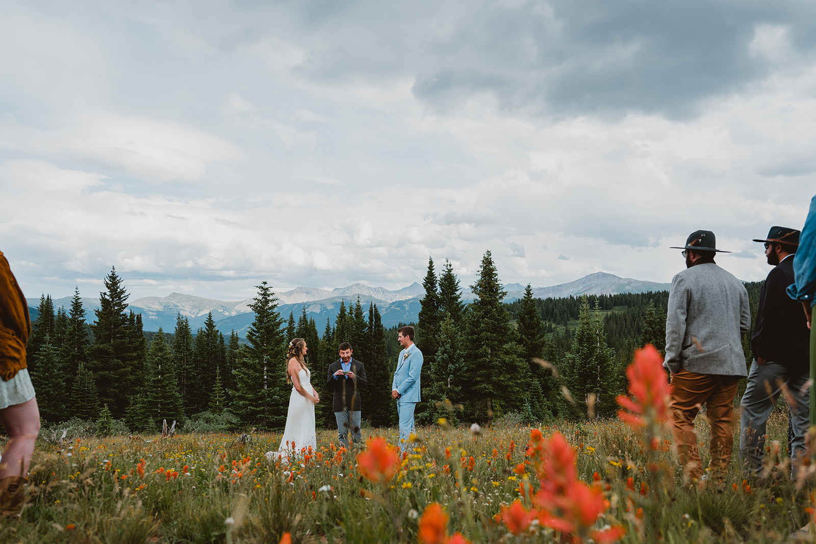 Shrine Pass Wildflower Wedding, Frisco, CO. Couple stands in wildflower field below the mountains for their ceremony.