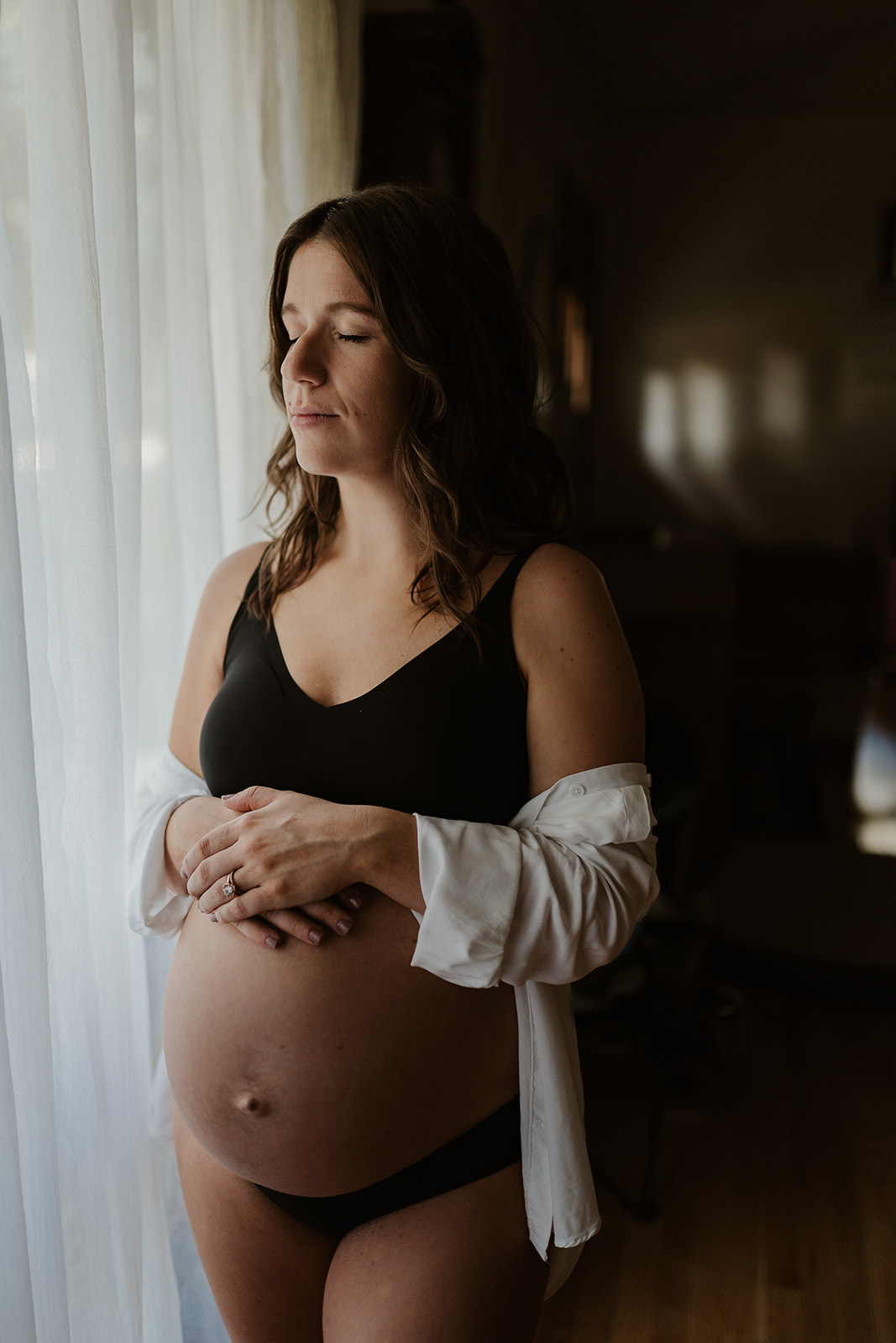 Maternity session in a Madison home with a new mama closing her eyes by the window