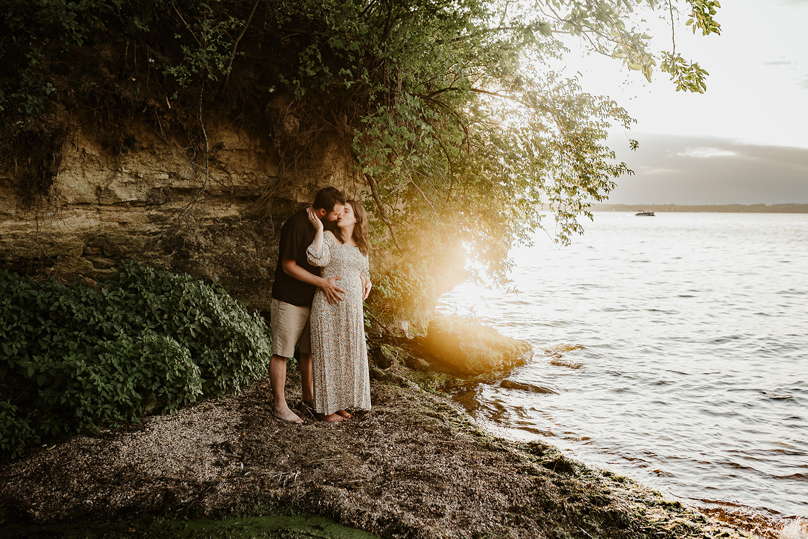 Pregnant couple kissing on the shores of a Madison lake