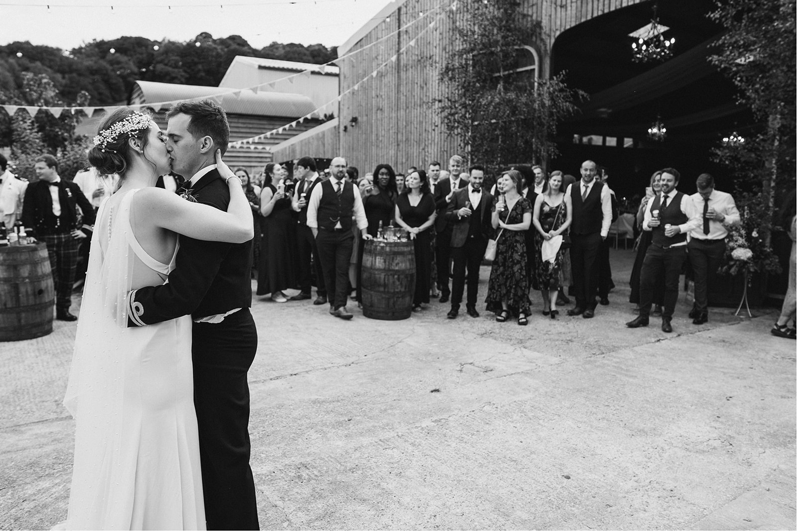 Derby DIY Farm Wedding Photography - bride and groom kiss during the first dance outside in the farm courtyard
