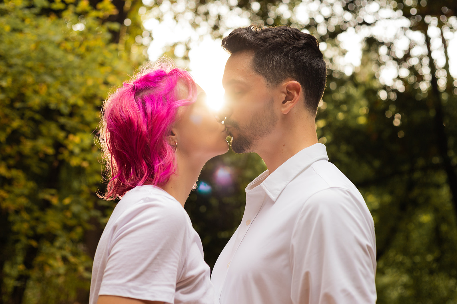 couple kiss with golden sun flare behind them
