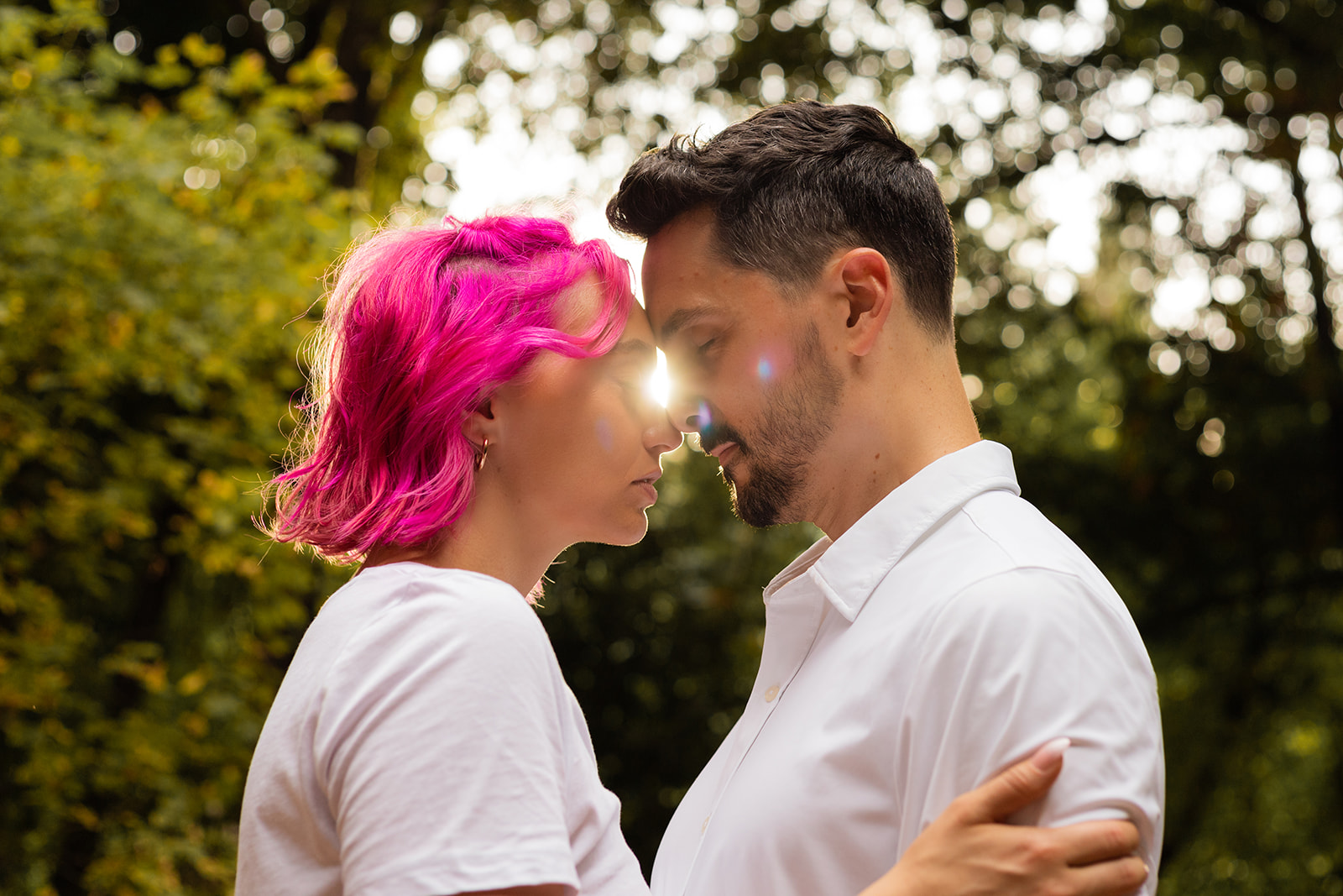couple touch foreheads tenderly as sunlight streams behind them