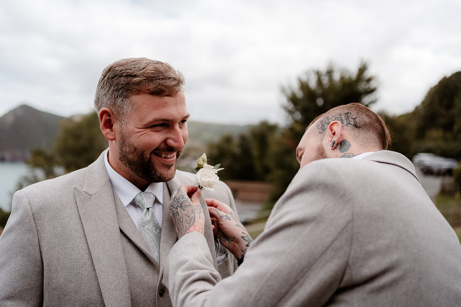 Best man pins buttonhole on groom's lapel at a Sandy Cove Hotel wedding