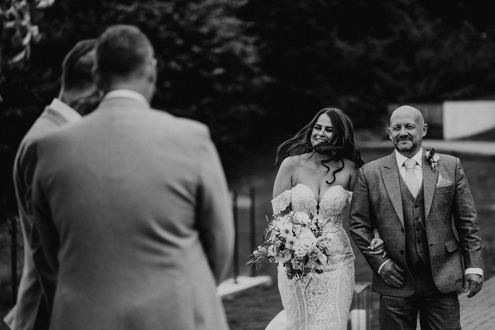 Black and white photo of the wind whipping the bride's hair as she walks down the aisle at her Sandy Cove Hotel wedding