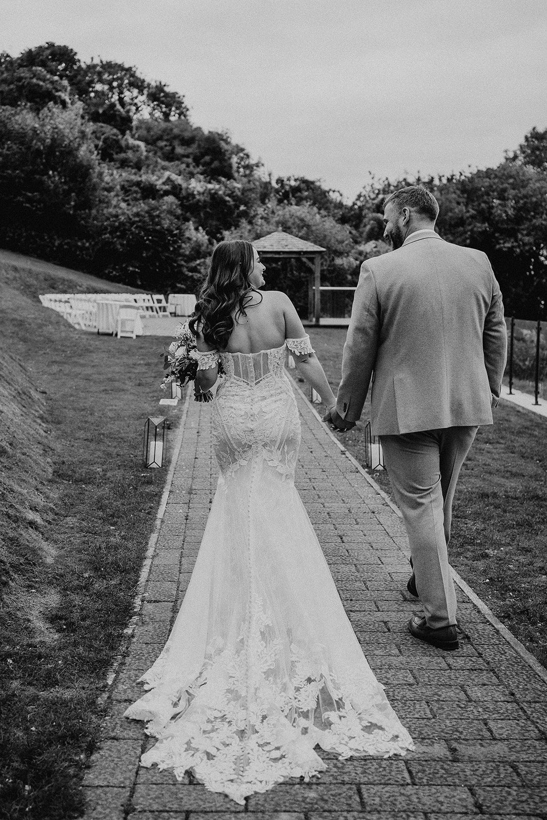 Black and white portrait of the bride and groom walking away from the camera at their Sandy Cove Hotel wedding