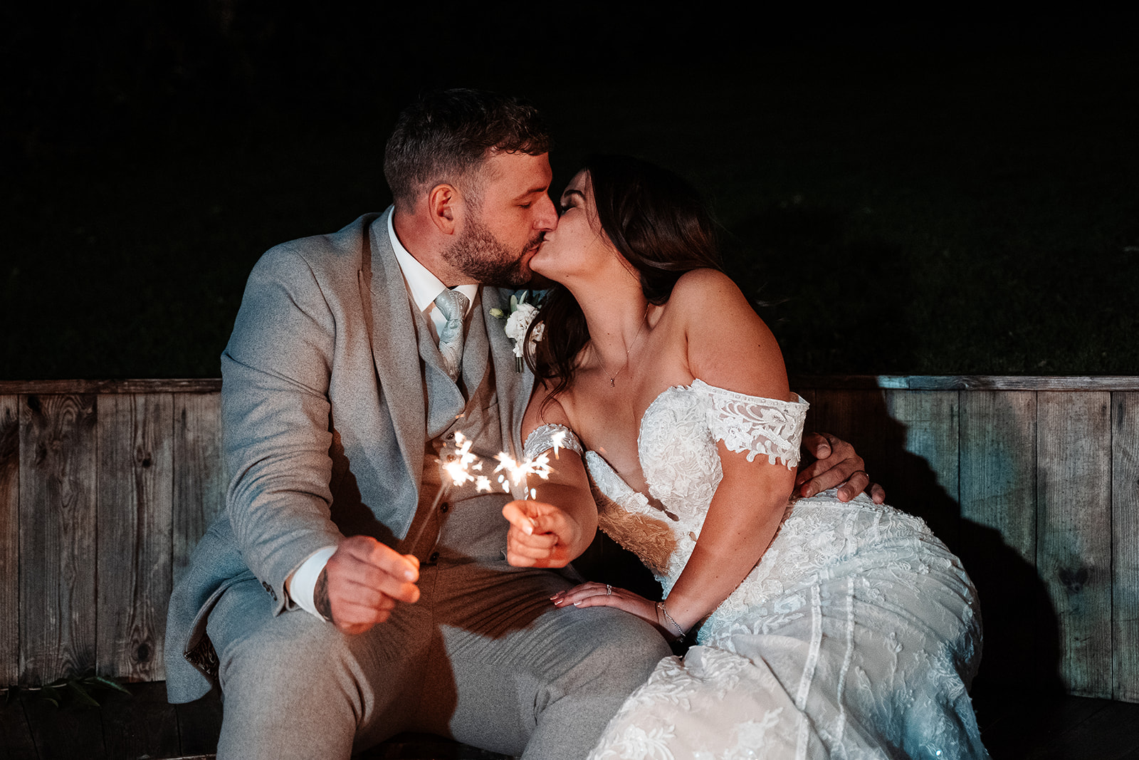 Bride and groom kiss while waving sparklers at their Sandy Cove Hotel wedding