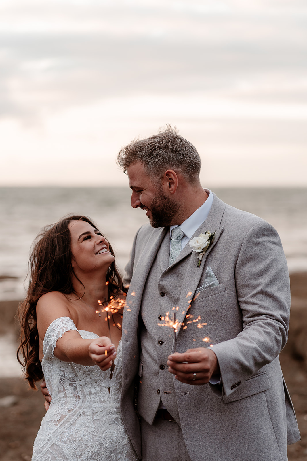 Bride and groom have a private sparkler moment on the beach at their Sandy Cove Hotel wedding