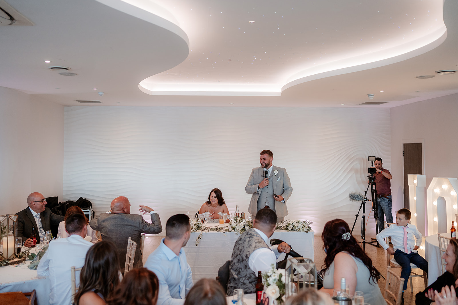 Groom gives a toast from the sweetheart table at a Sandy Cove Hotel wedding breakfast