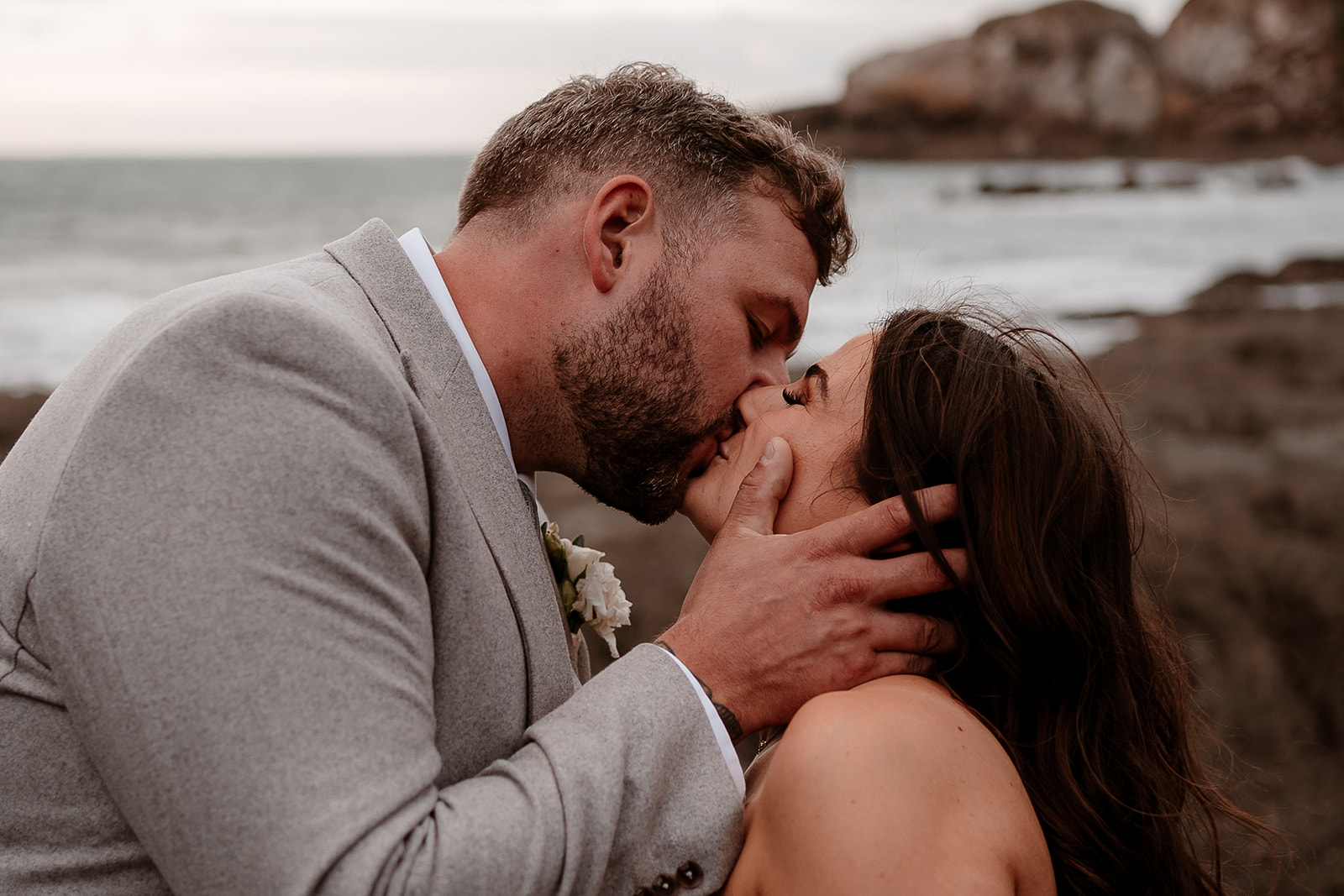 Groom kisses his bride on the beach at their Sandy Cove Hotel wedding