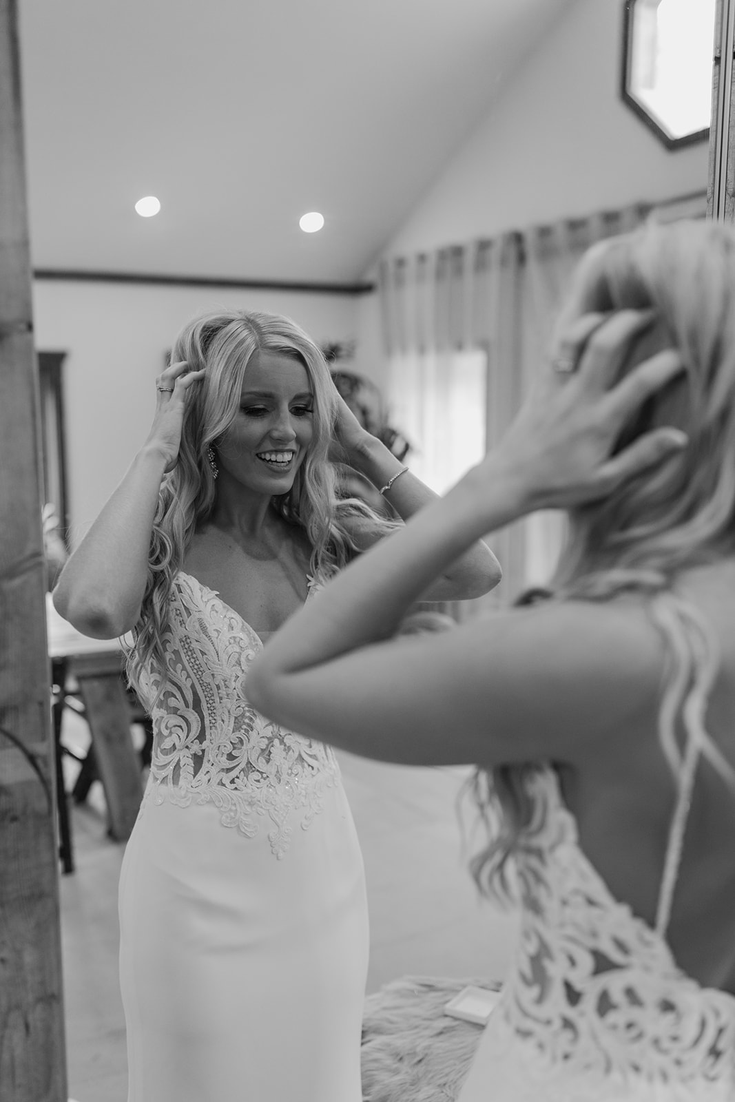 Bride puts on her earrings in front of a mirror