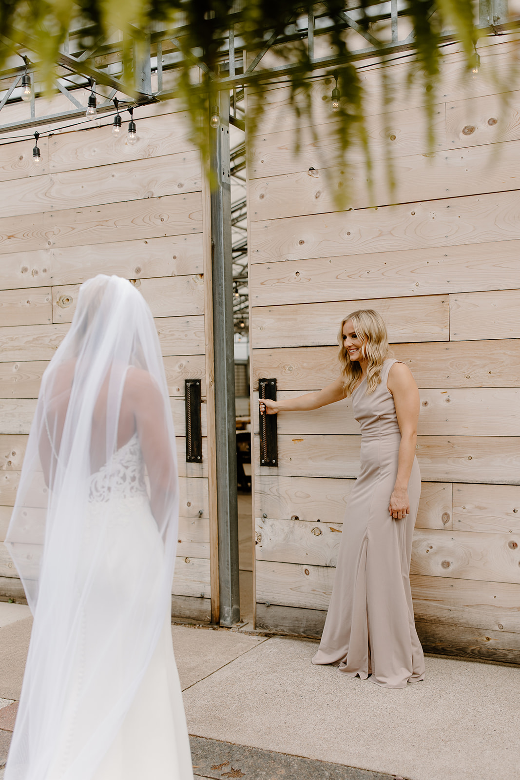 Maid of honor opens the door for her sister to see her groom