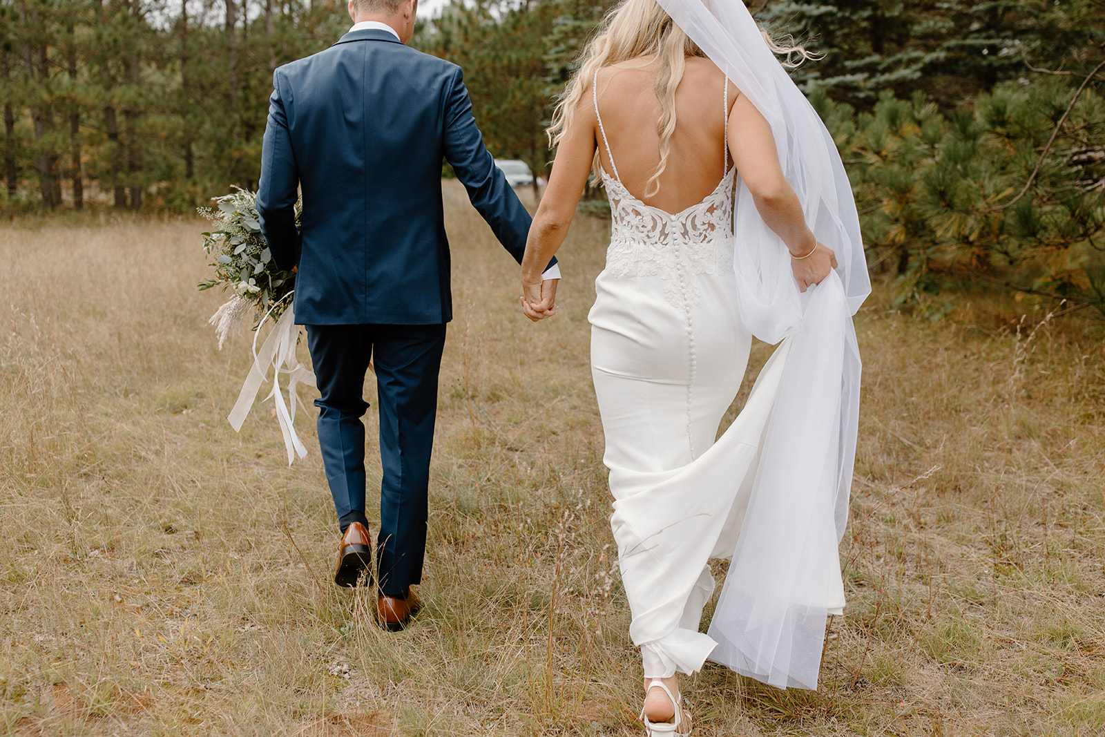 Bride and groom hold hands while walking away