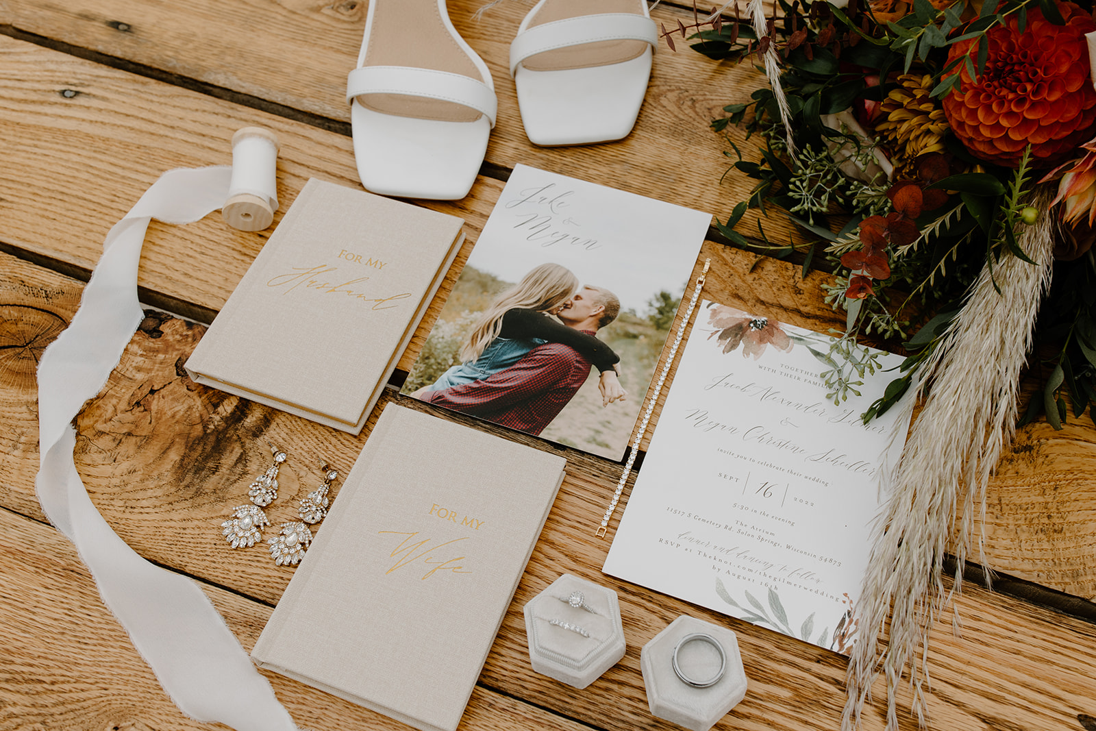 Wedding invitations, rings, and jewelry in a flat lay