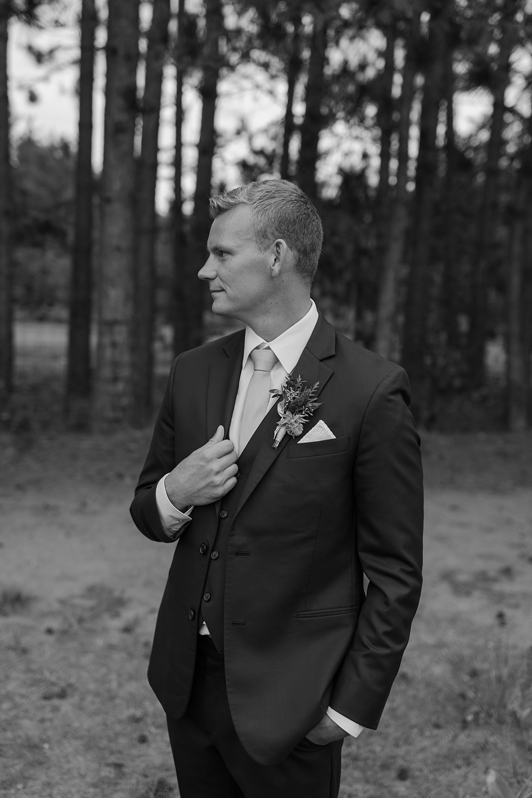 Groom looks away from the camera while holding his lapel