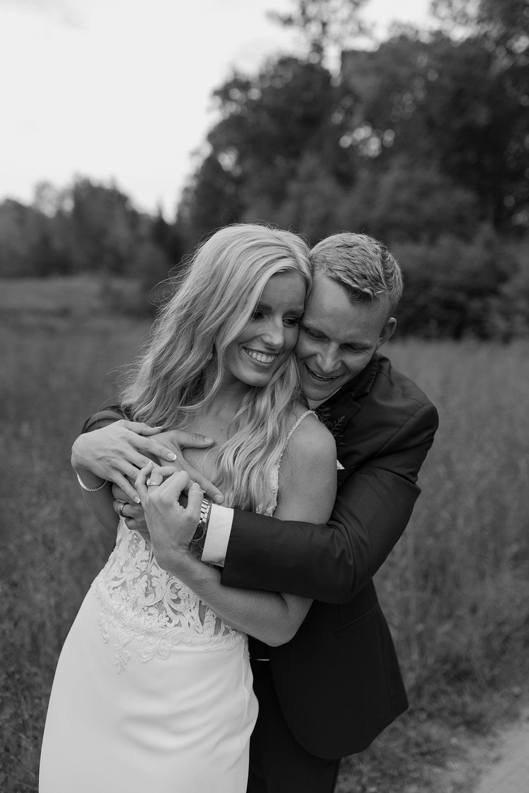 Bride and groom hug in a field of grass