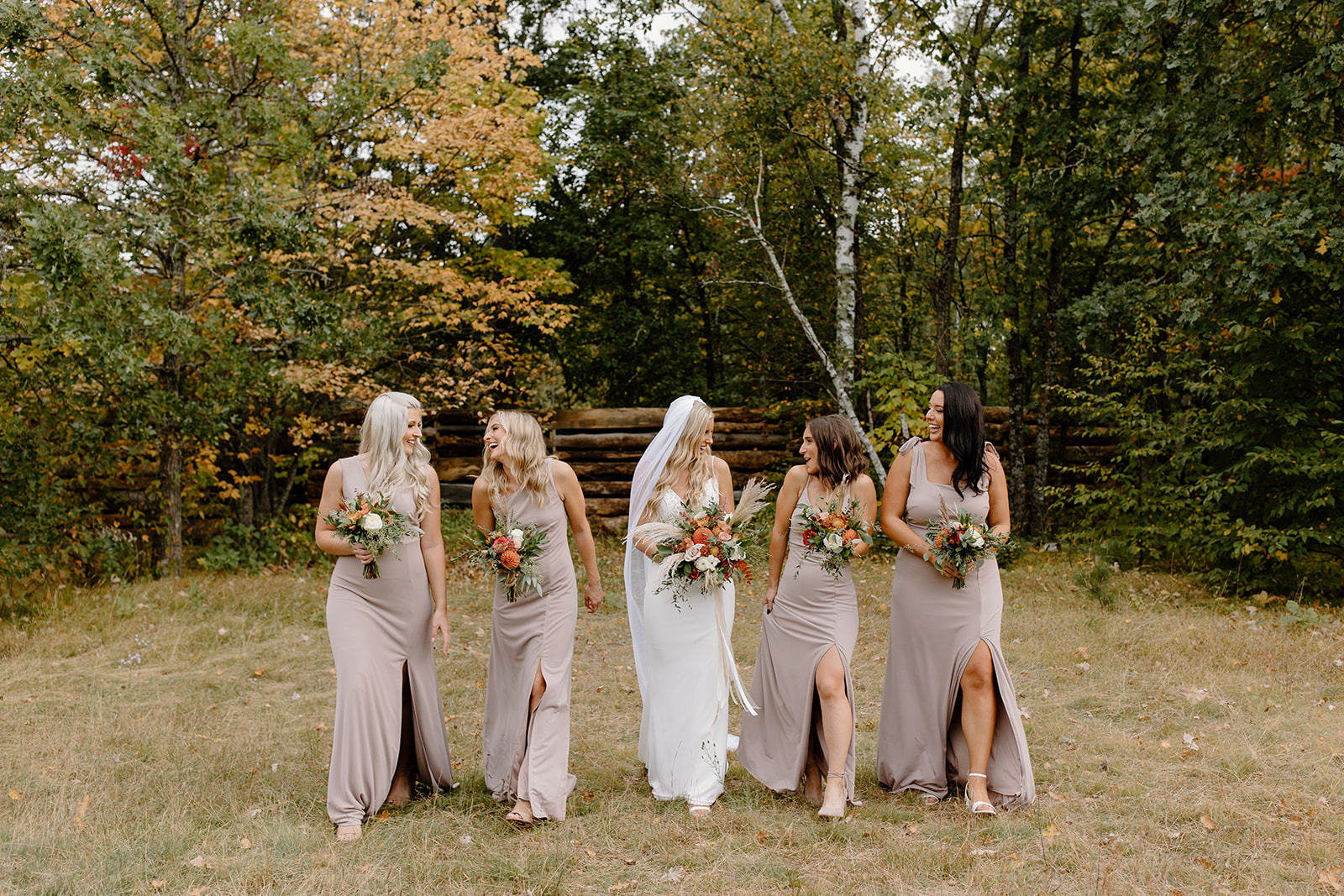 Bride and groom with their wedding party in front of trees with leaves changing color