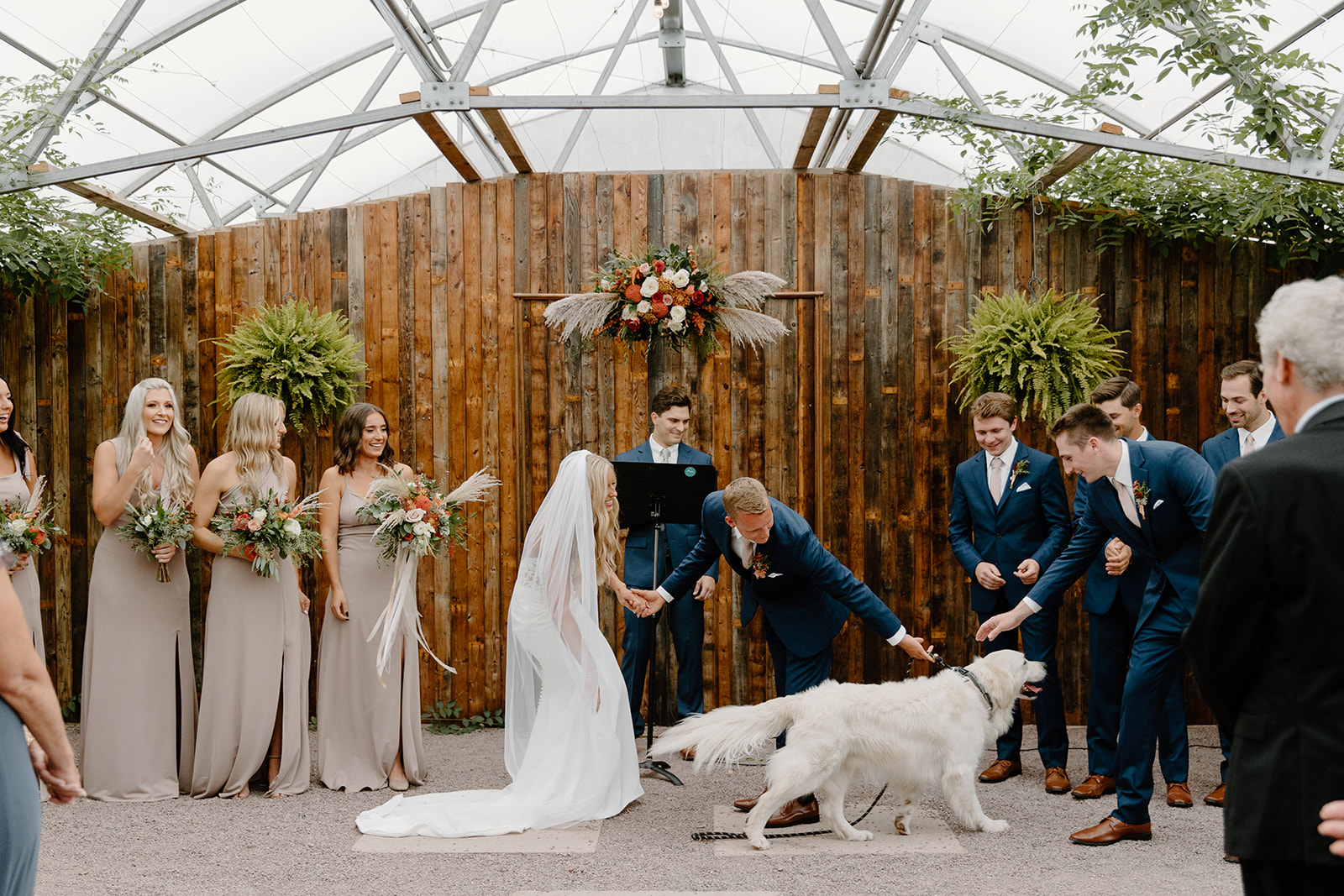 Bride and groom greet dog at the end of the aisle