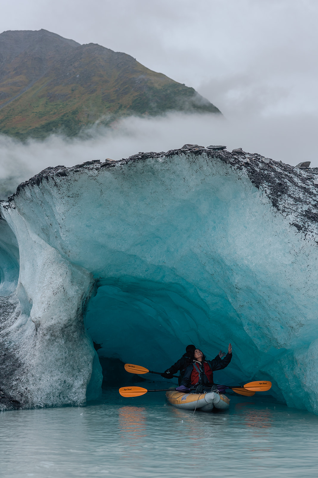 couple kayaks into ice caves in a glacier lake in alaska for their destination wedding