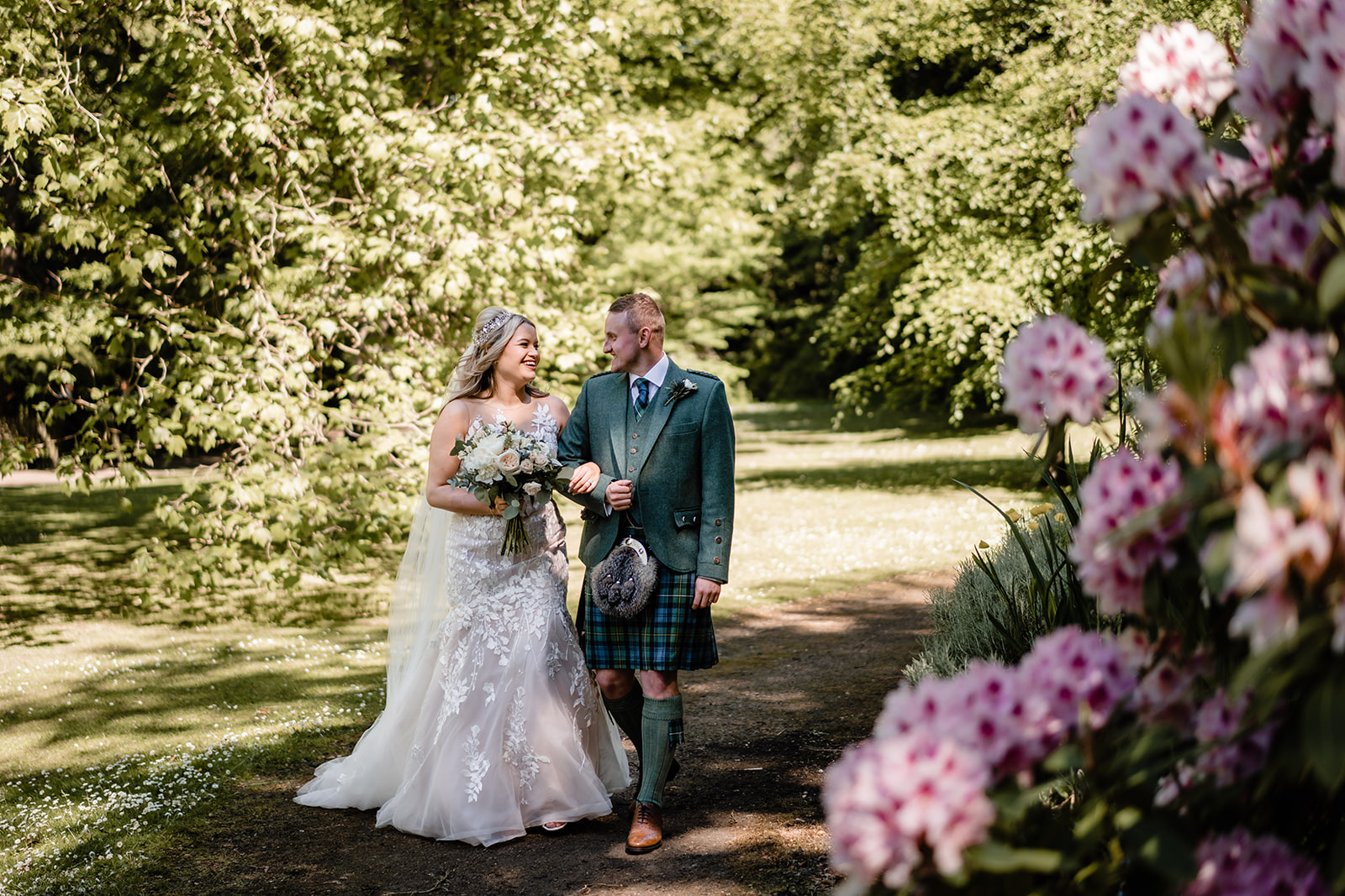newlyweds walking through queen street gardens, Edinburgh for their first wedding photos.