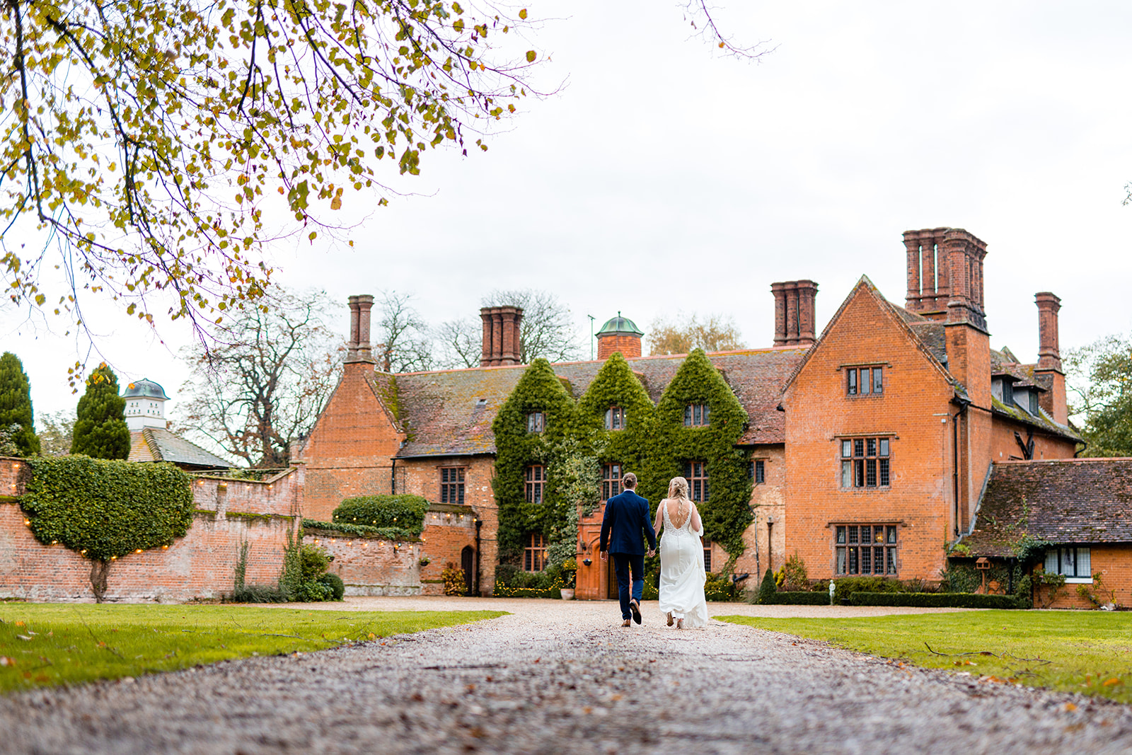 Couple walking up the driveway of Woodhall Manor by Martin Beale Photography