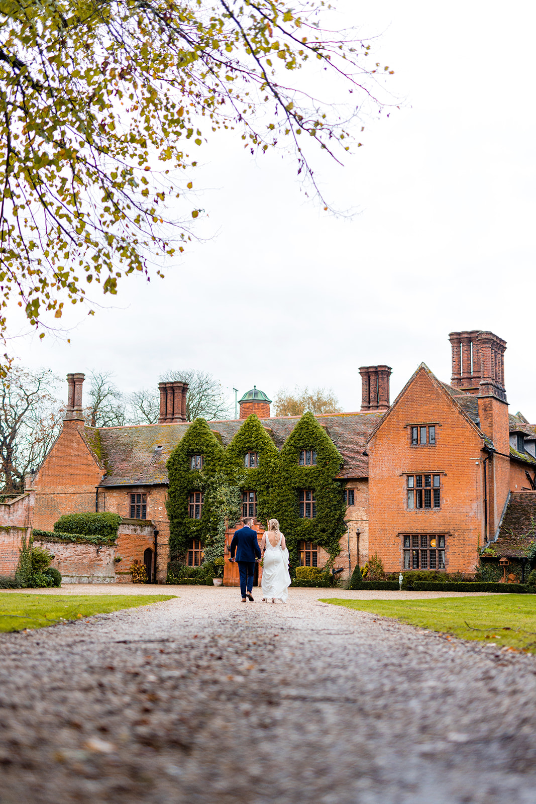 Couple walking up the driveway of Woodhall Manor by Martin Beale Photography