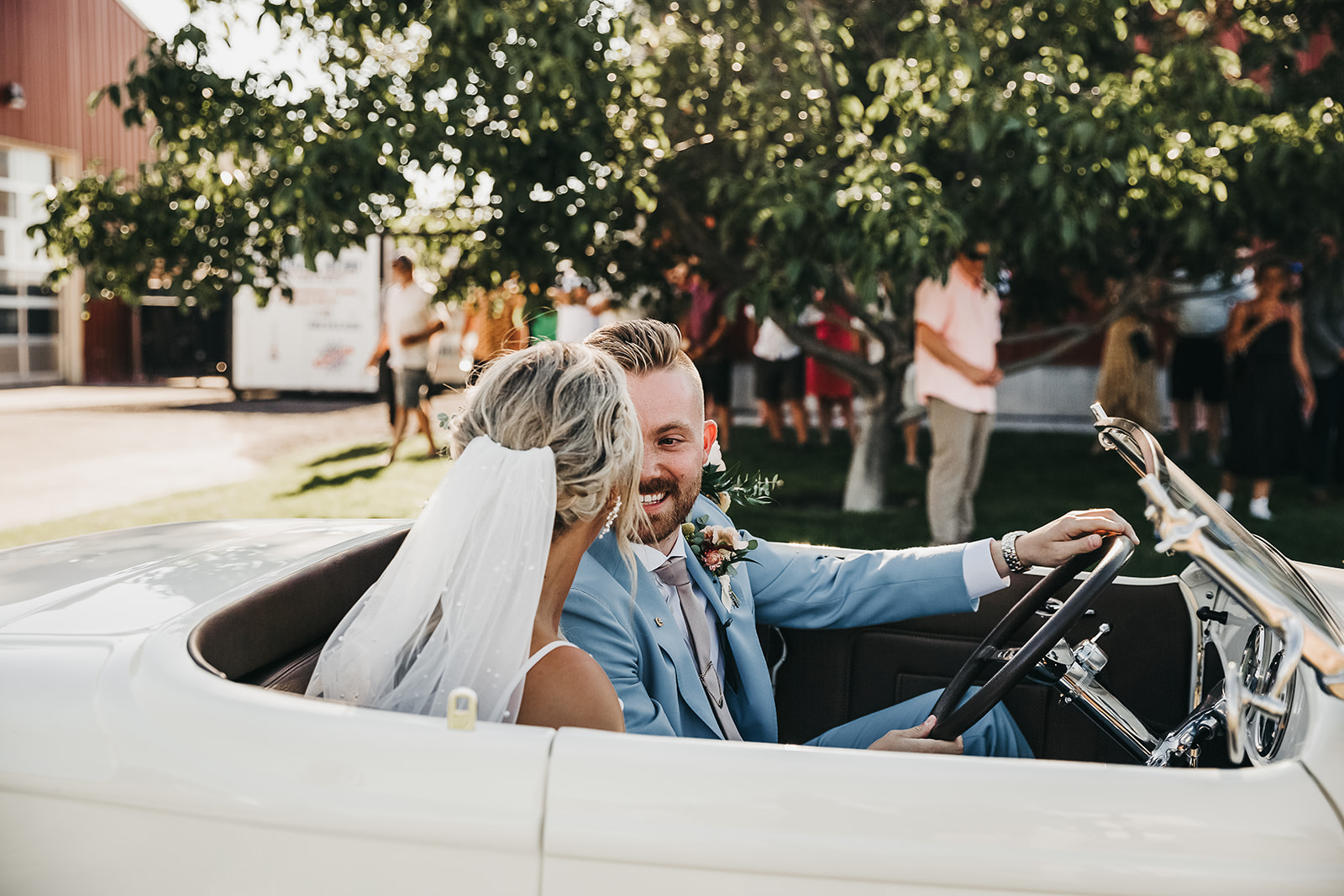 Bride and groom drive away in white classic car after just saying I do