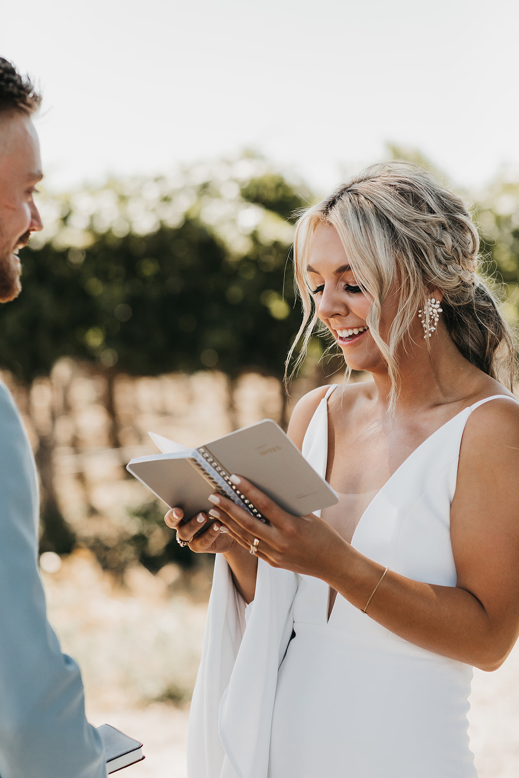 Bride reading vows to groom before wedding surrounded by beautiful rows wine vineyard in Washington