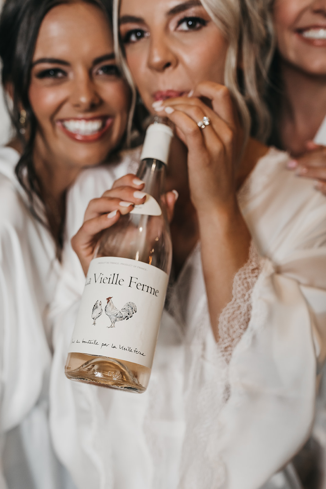 Bride sipping on wine through a straw straight out of the bottle while getting ready