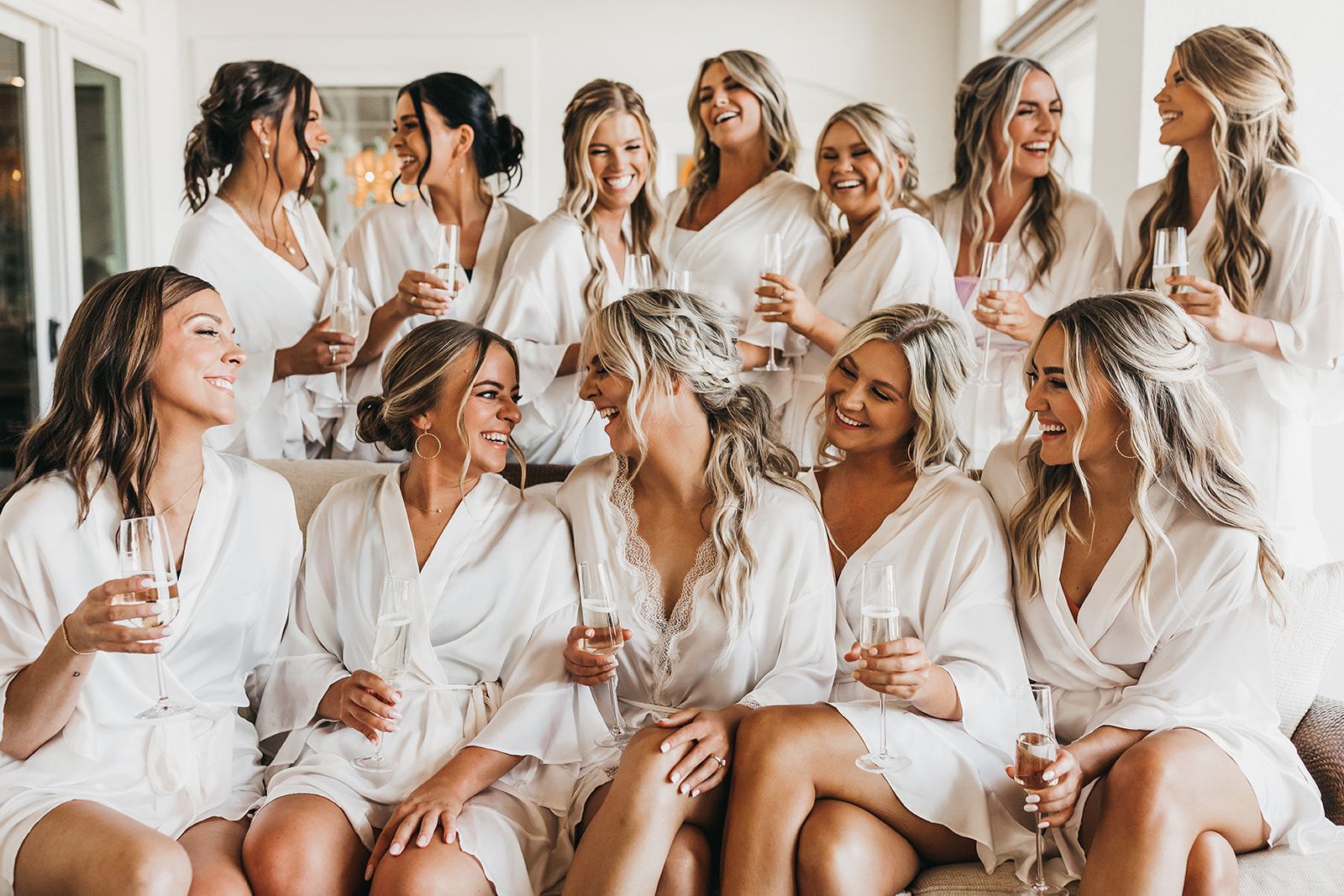 Bride and bridesmaids drinking together in matching silk robes while getting ready for wedding