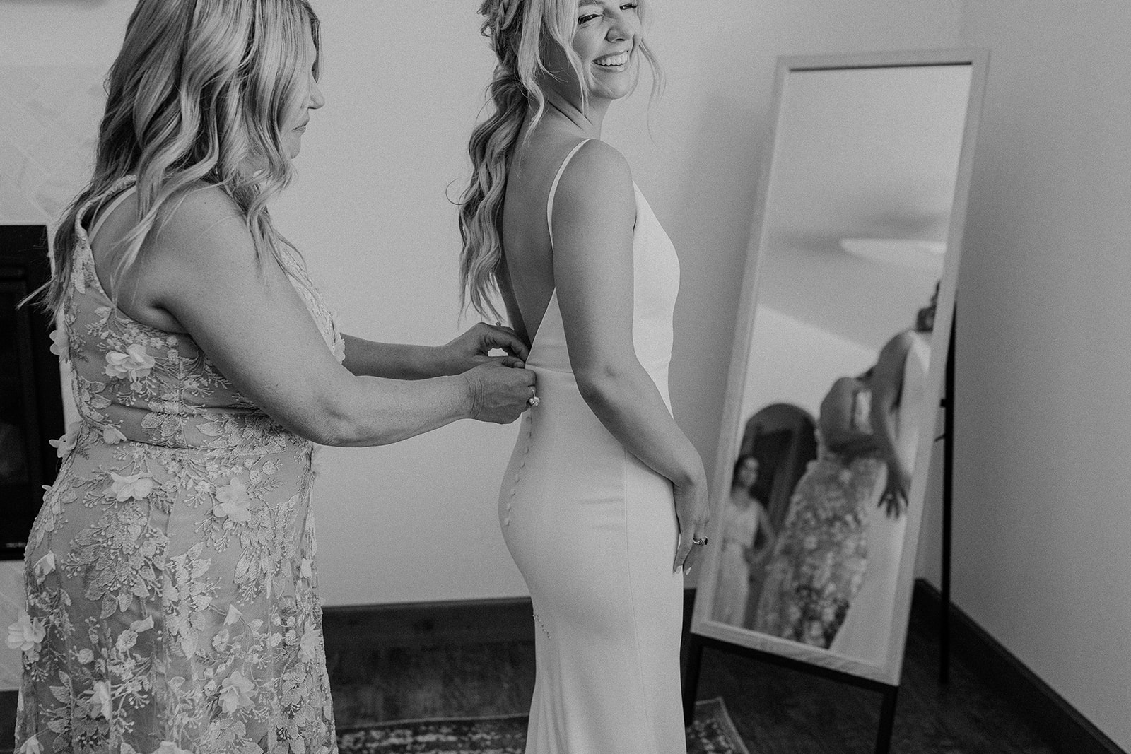 Mother of the bride helping bride put on her dress by Alyssa Kristin before wedding ceremony