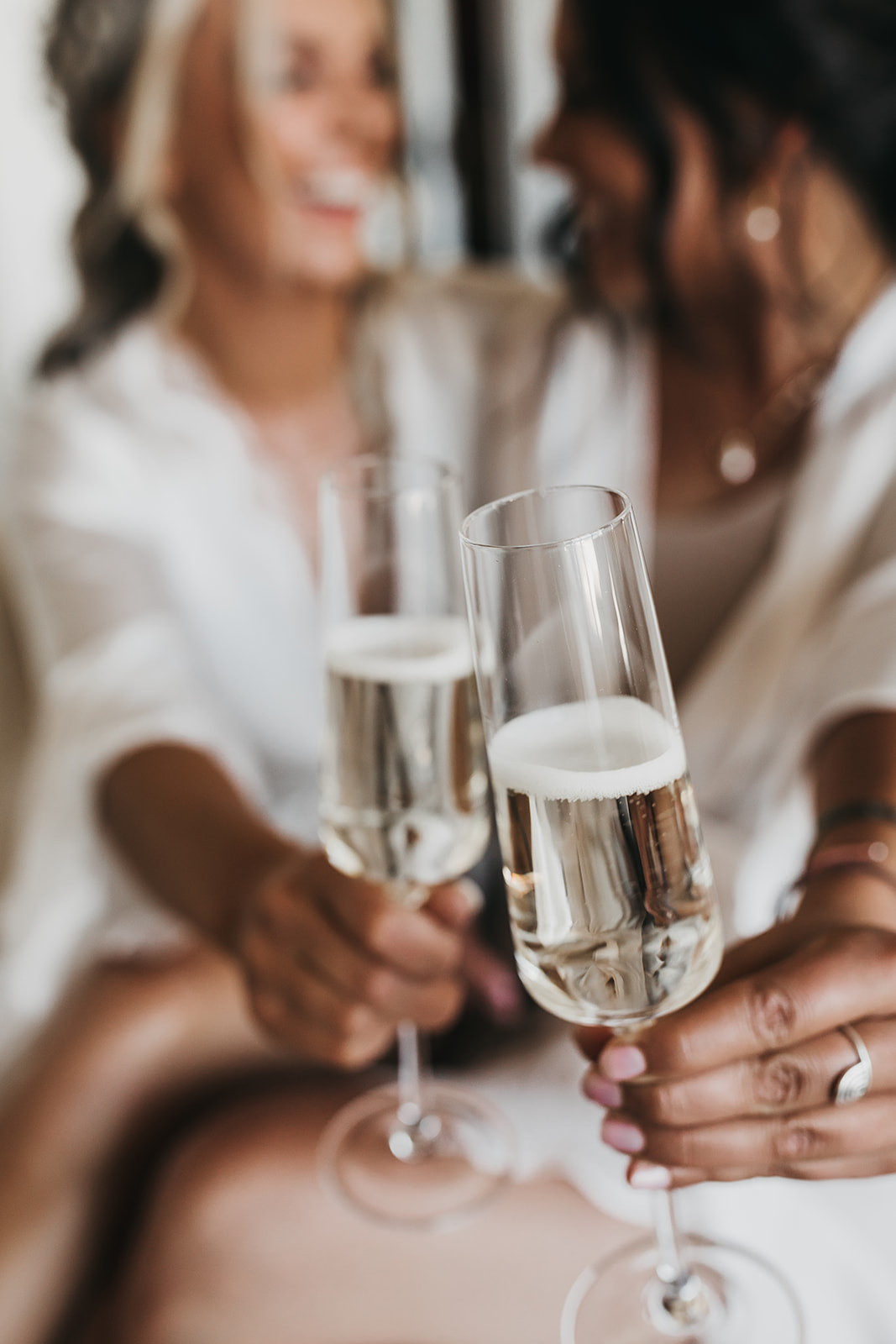 Bride and bridesmaid sharing champagne while getting ready 