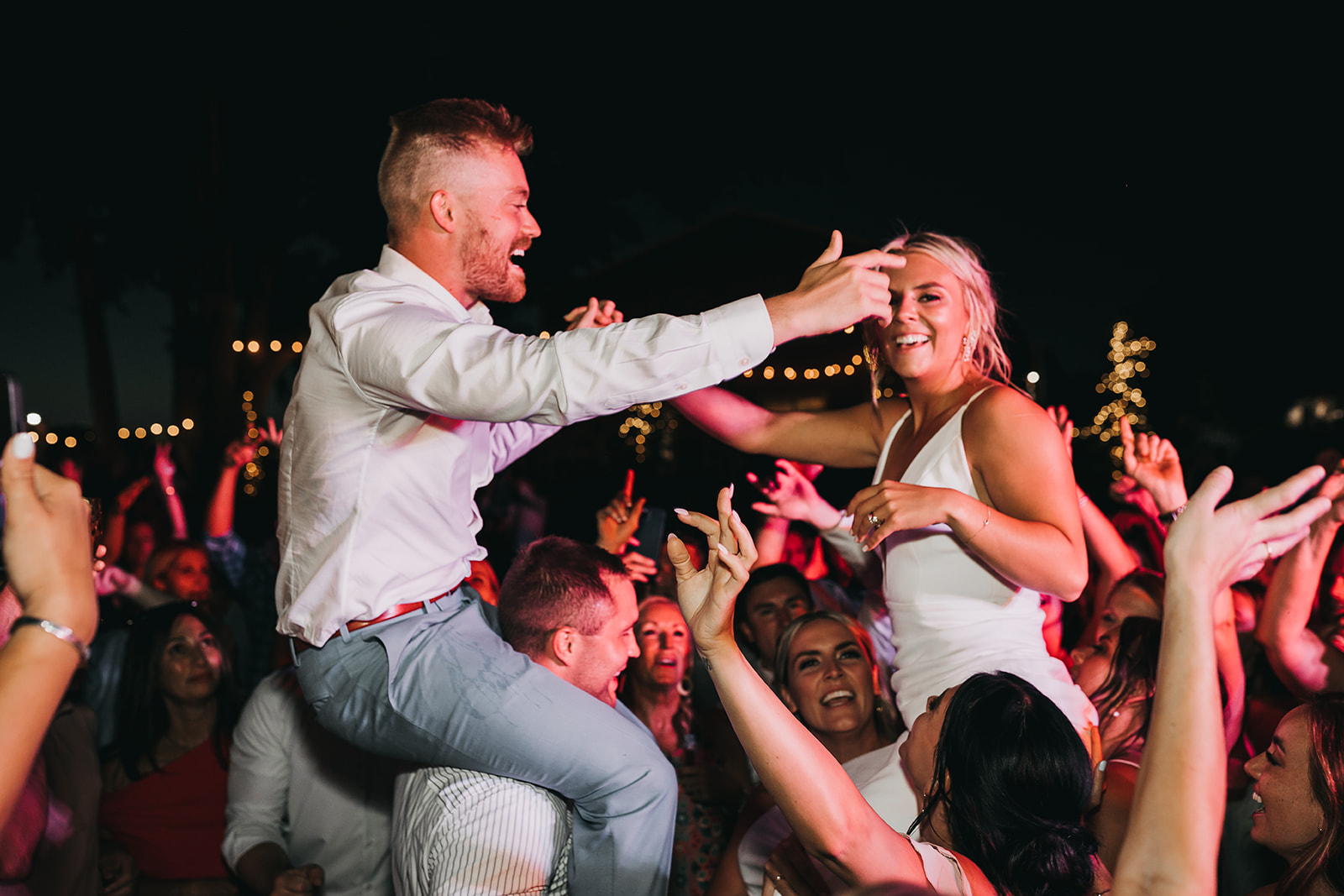 Bride and groom getting lifted up on guest shoulders and have a blast at wedding reception