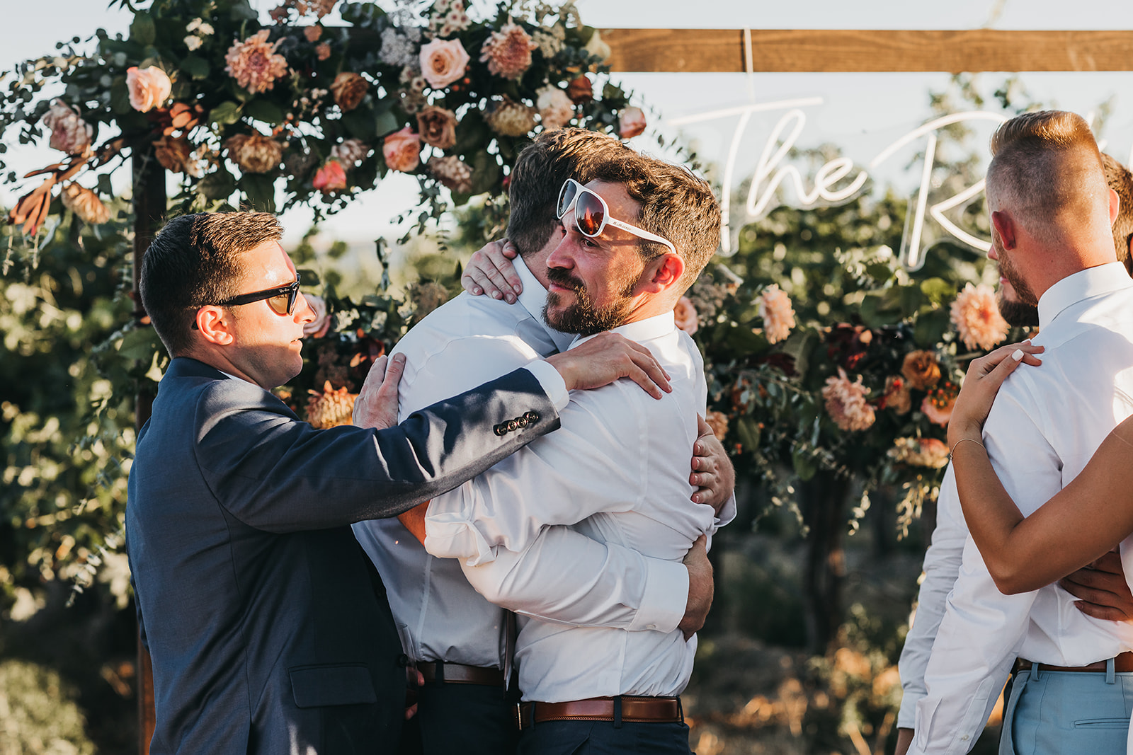 Groom and groomsmen hugging at wedding reception at Cooper Wine Company winery wedding