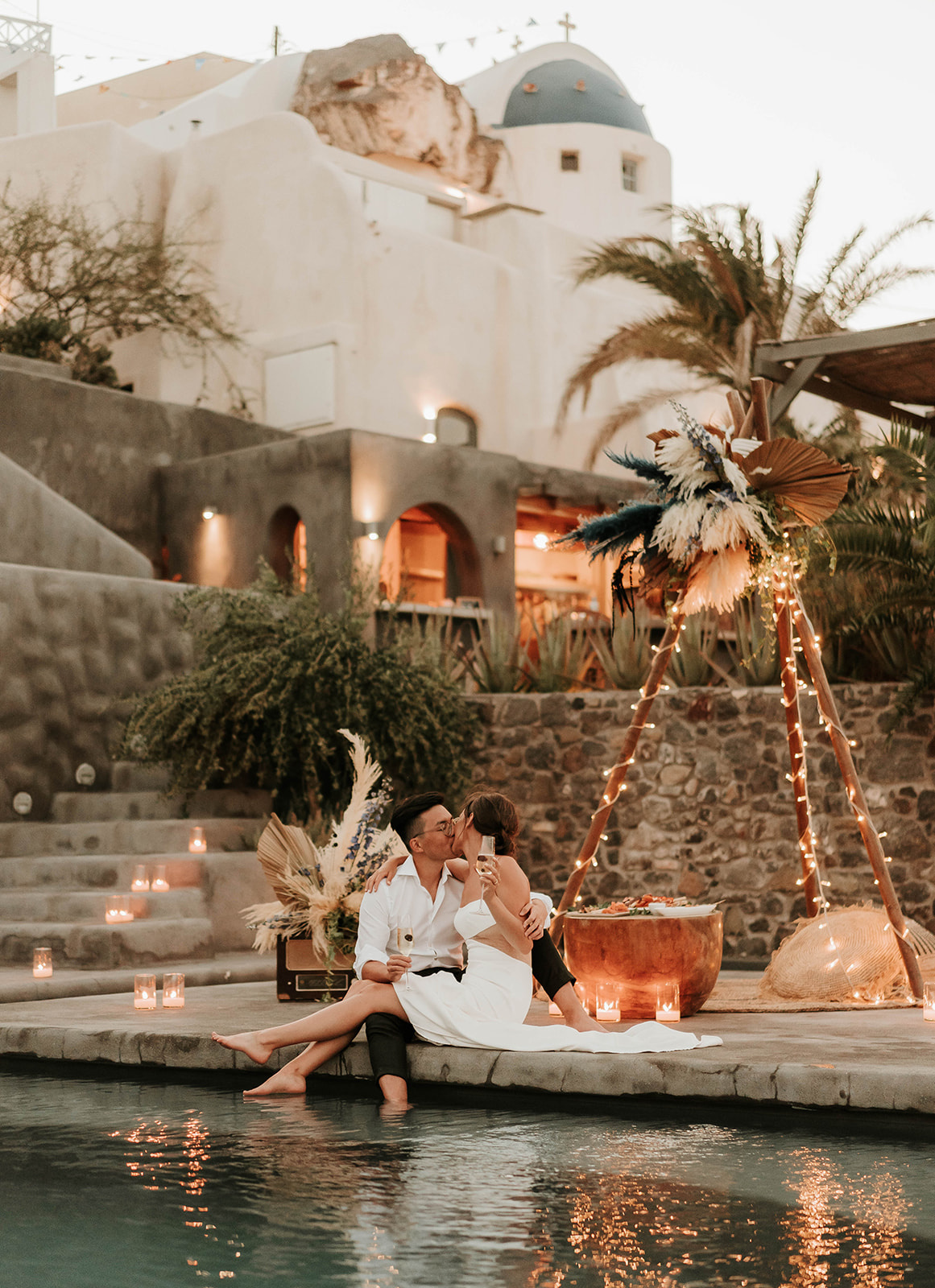 A couple who eloped in Santorini enjoy their evening meal by the pool with candles
