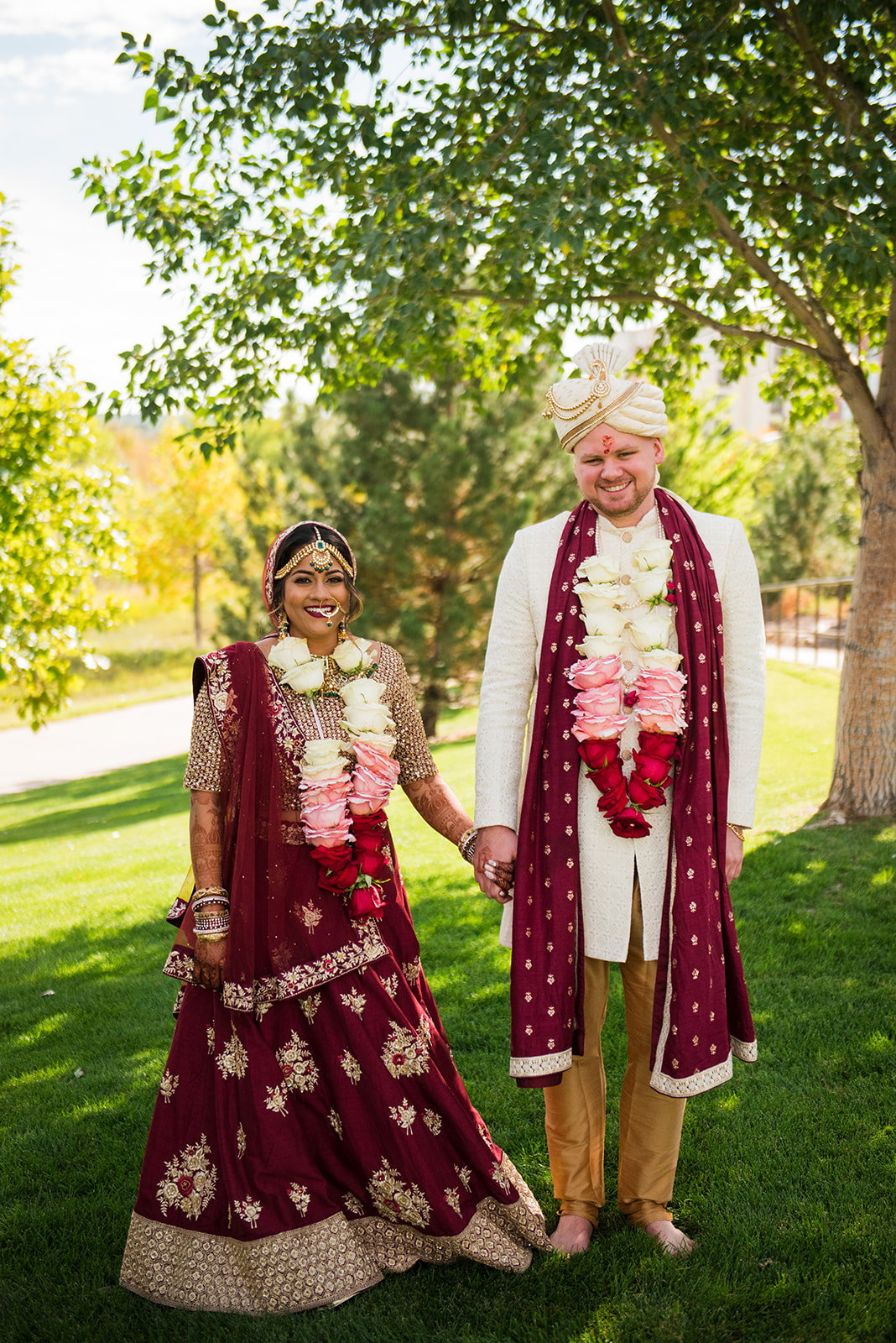 Bride and groom stand facing the camera in their traditional Indian saris.