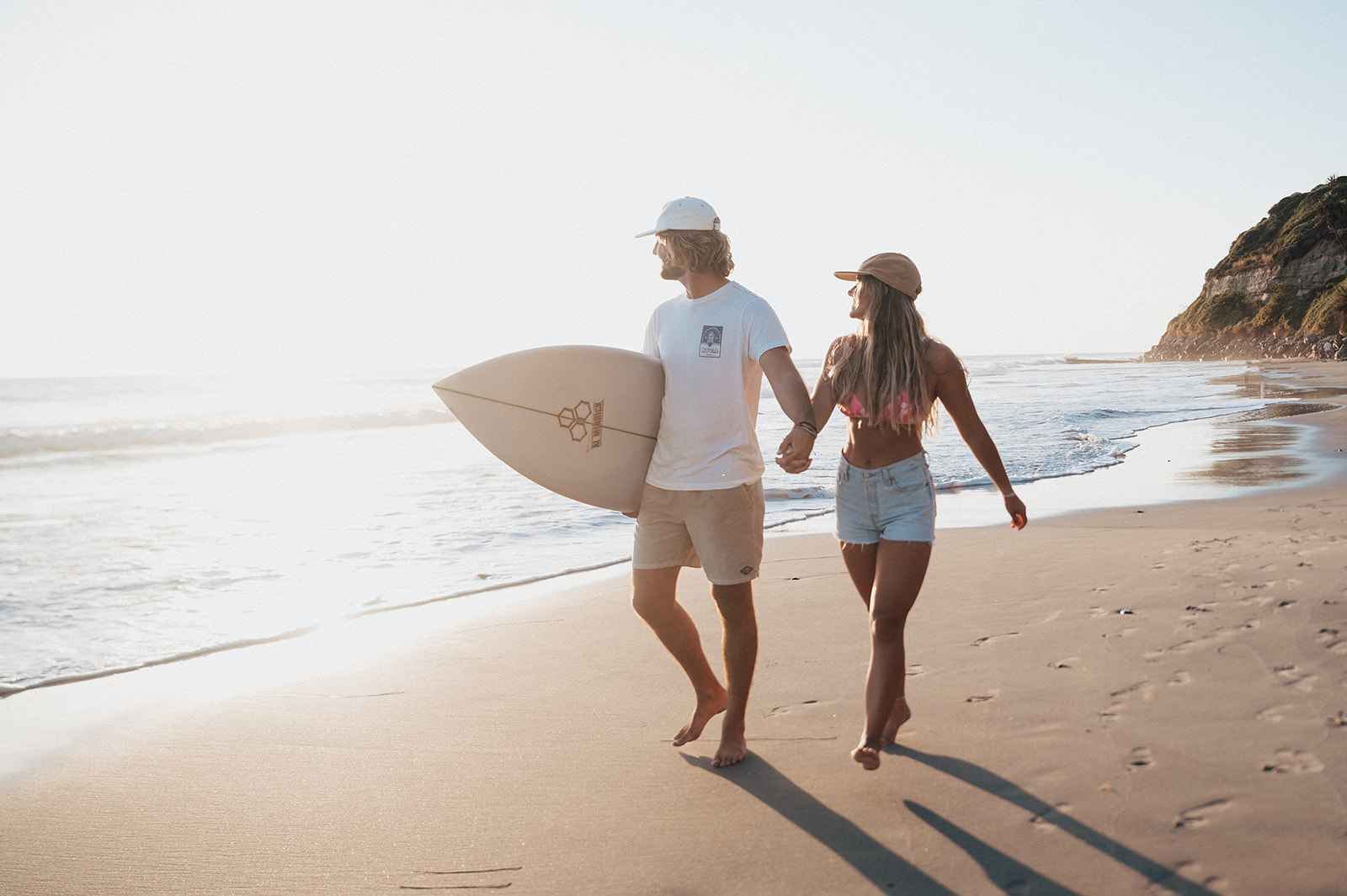 surfer couple walk along the California beach during a couples session