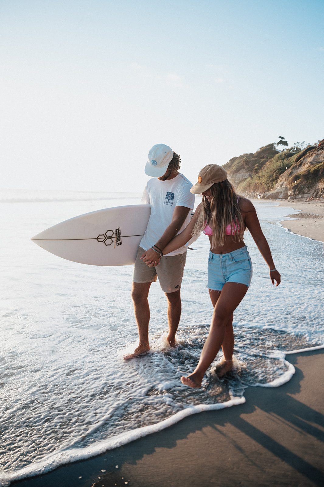 surfer couple walk along the California beach during a couples session