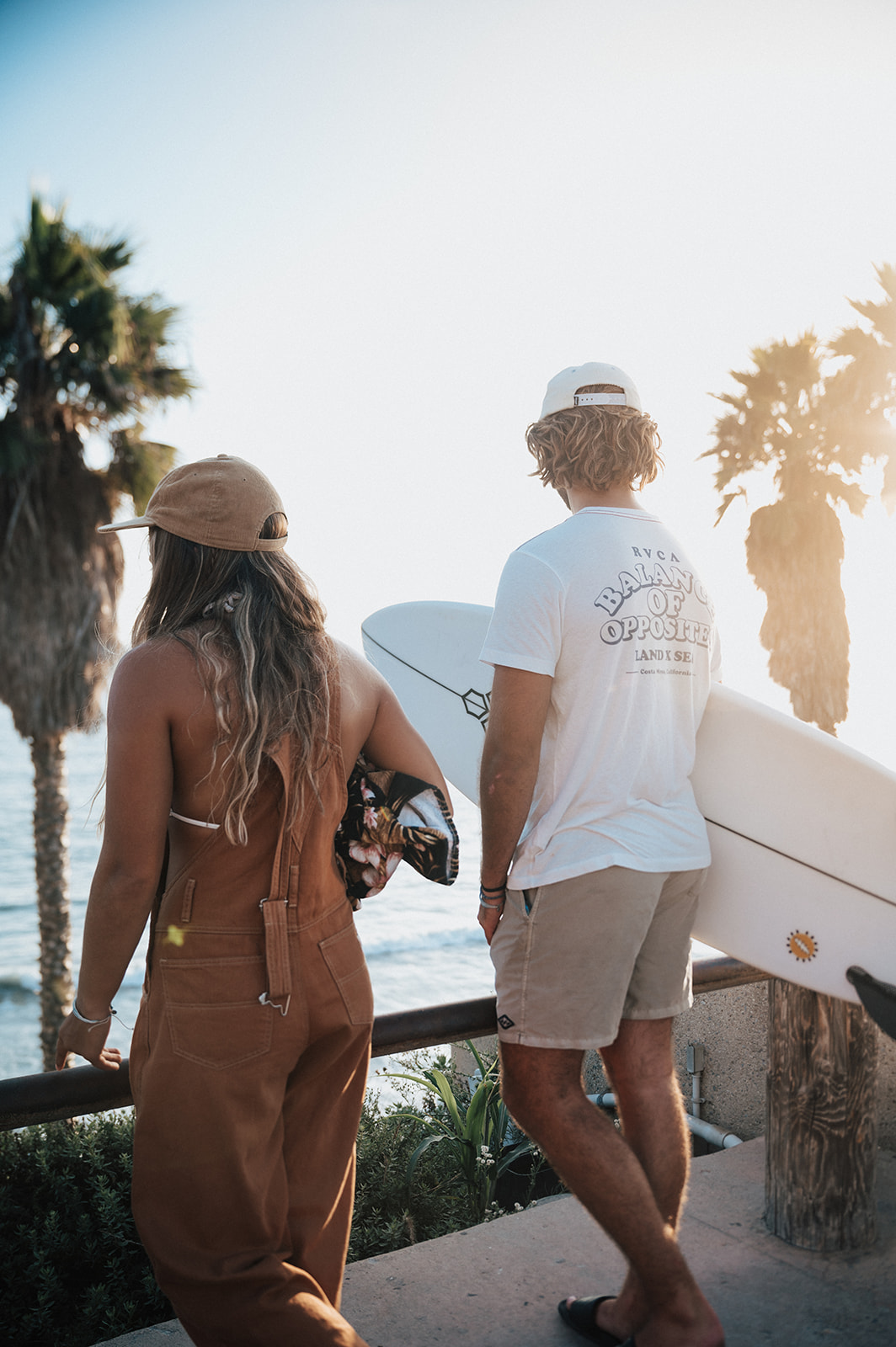 Surfer couple looks out over the ocean at golden hour