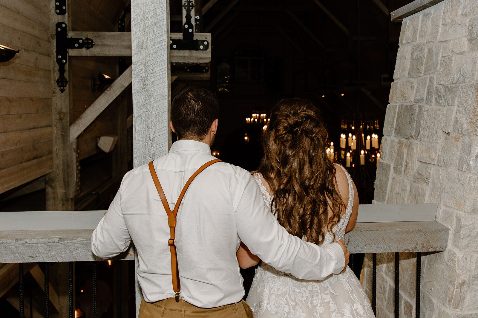 Bride and groom watch their guests dance from a balcony