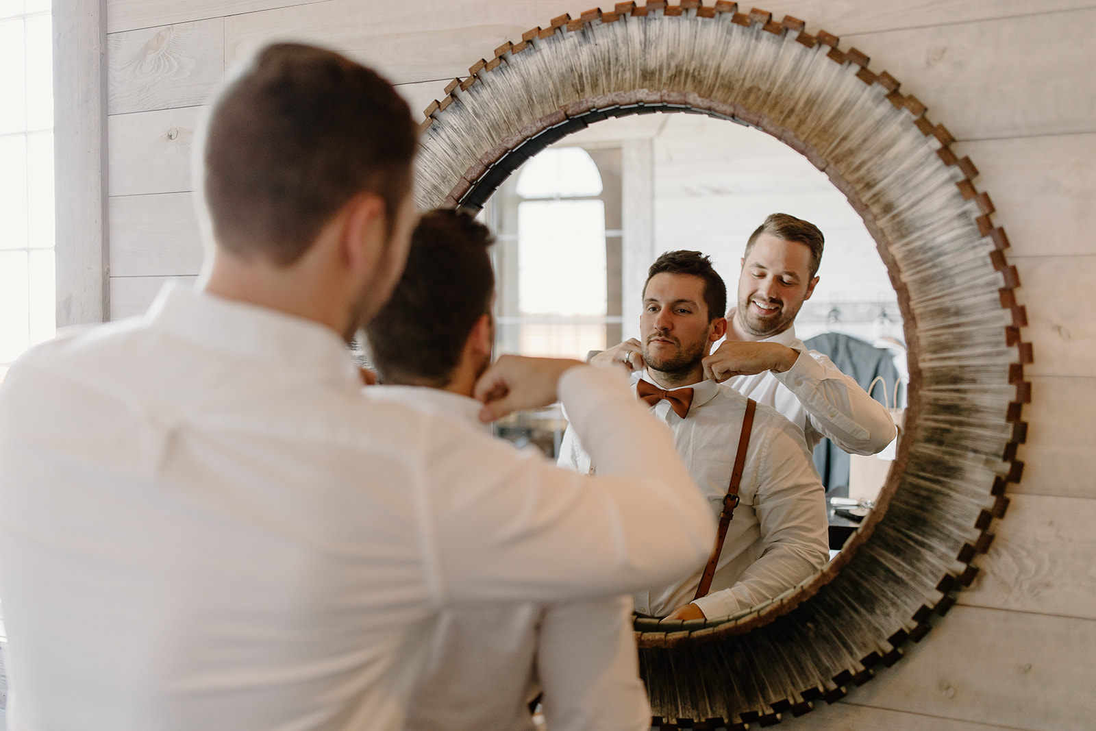Groomsmen ties groom's tie in front of mirror