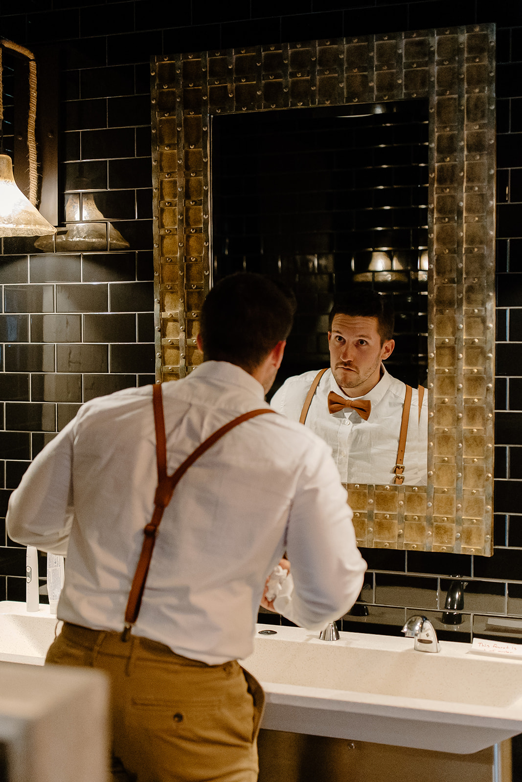 Groom gets ready in front of mirror