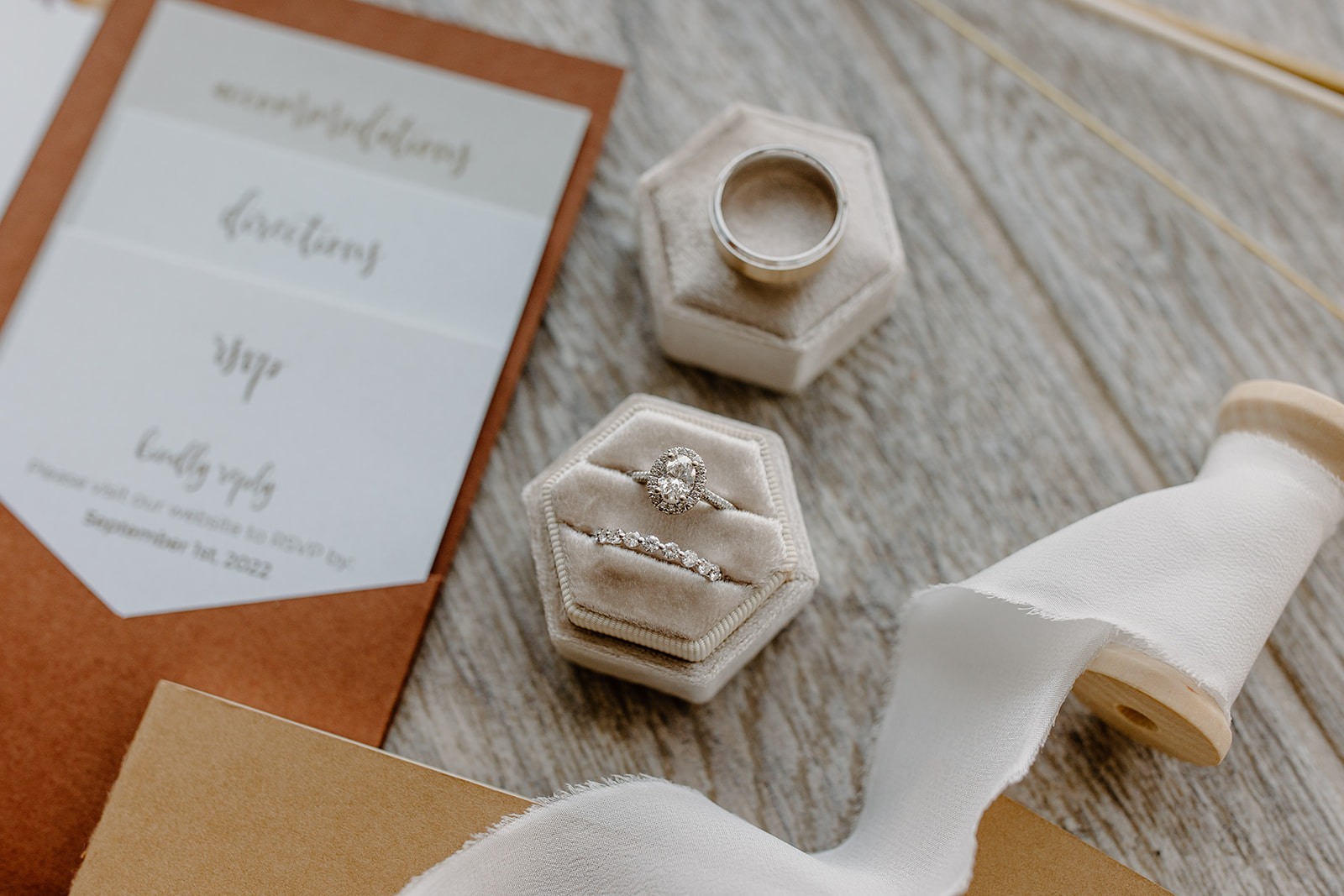 Flat lay of wedding invitations, rings, jewelry, and other details