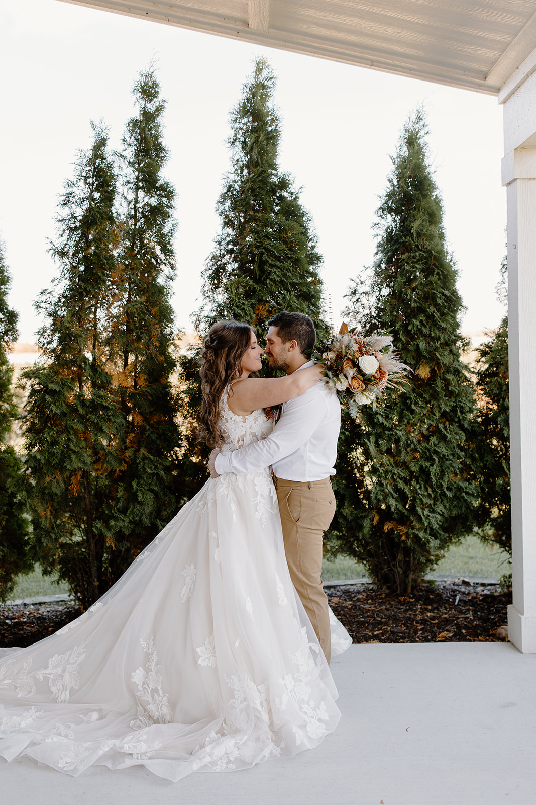 Bride and groom hug in front of trees