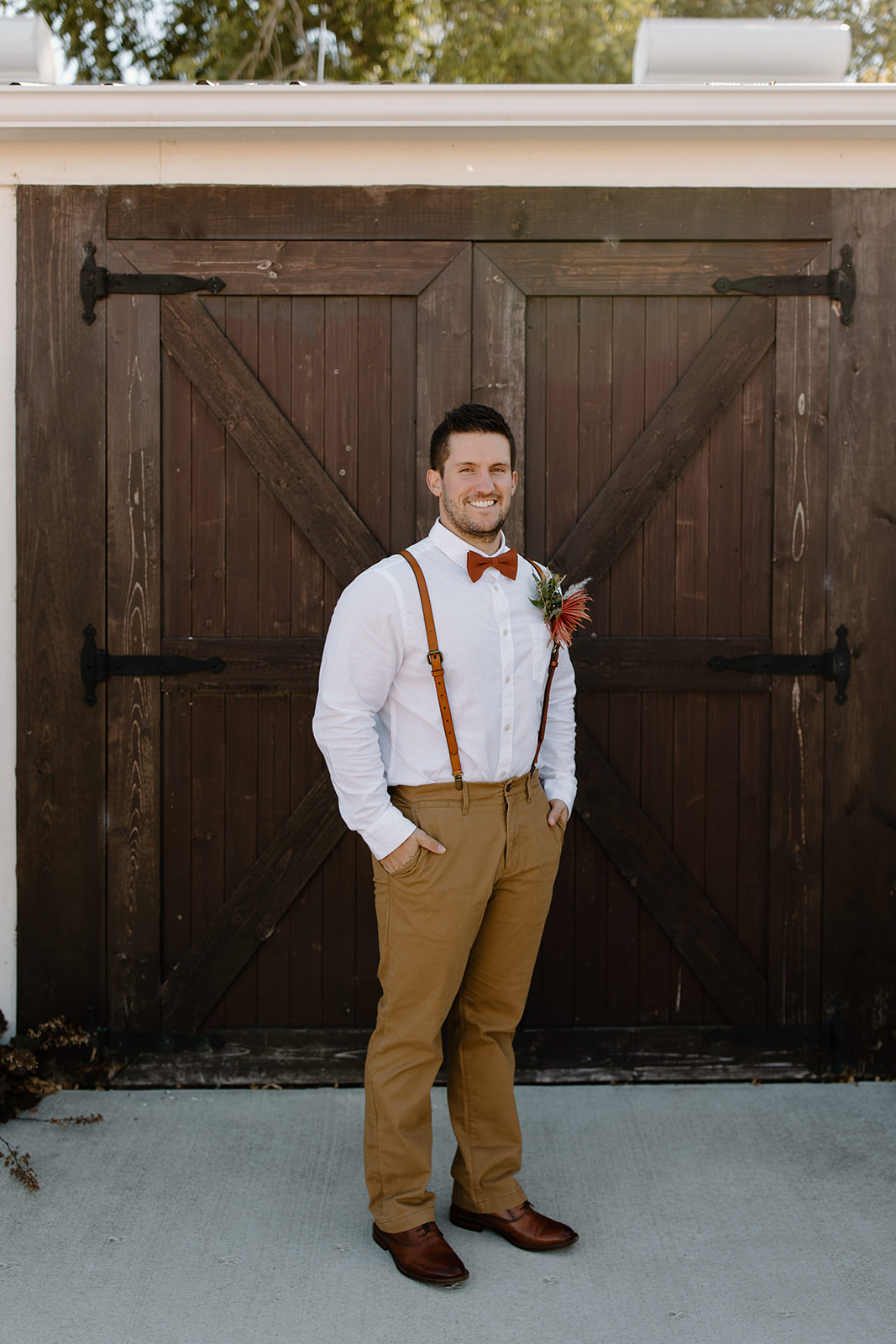 Groom smiles in front of a barn door