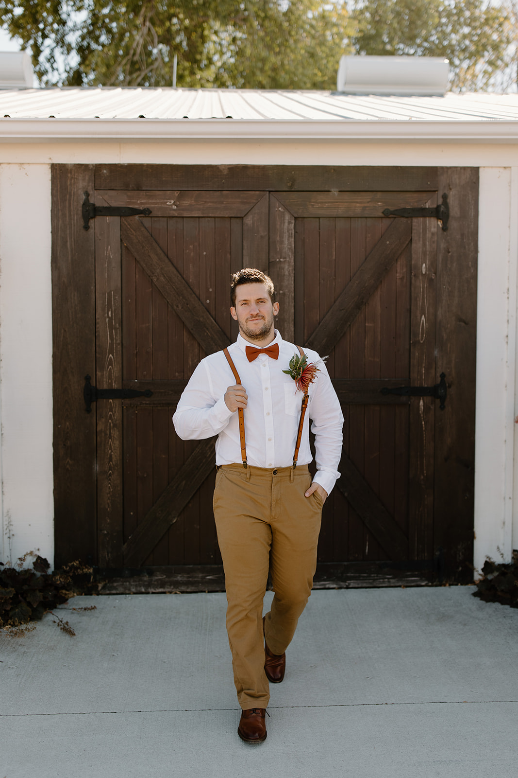 Groom smiles in front of a barn door