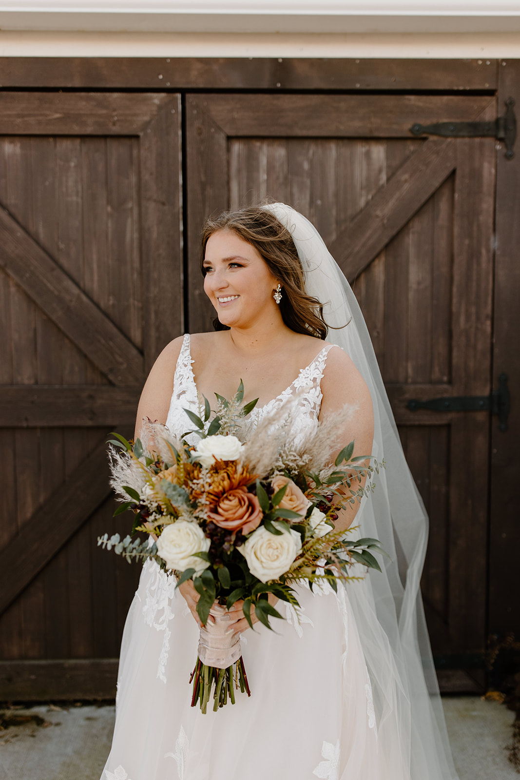Bride smiles in front of a barn door