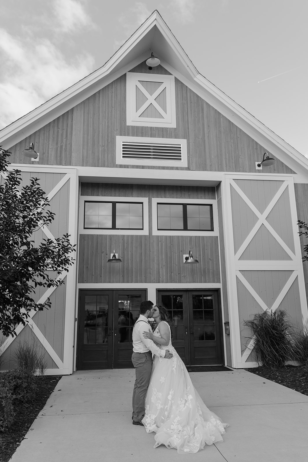 Bride and groom kiss in front of a barn