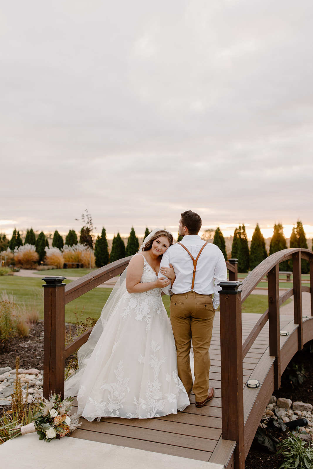 Bride and groom on top of a bridge with the sunset in the background